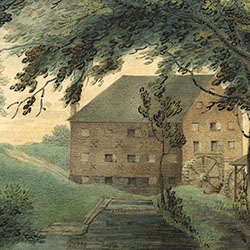 Water runs towards multi-storied industrial building containing two water wheels on side façade. Building surrounded by trees and rolling hills